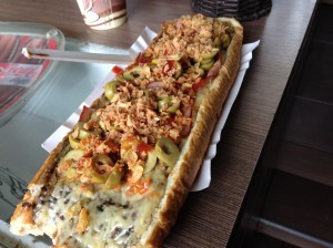 This zapiekanka is topped with green olives and crispy onion bits, while the base below the cheese is a mushroom sauce.